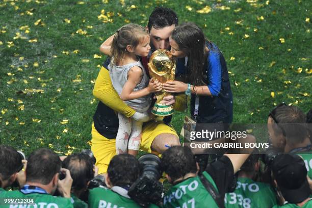 France's goalkeeper Hugo Lloris kisses the trophy with his daughters as they celebrate during the trophy ceremony after winning the Russia 2018 World...