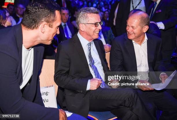 The former boxer Vladimir Klitschko , German federal minister of interior affairs Thomas de Maiziere nad Hamburg's mayor Olaf Scholz sit together...