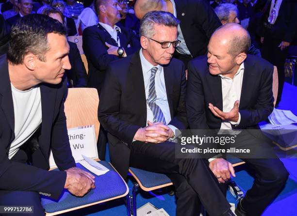 The former boxer Vladimir Klitschko , German federal minister of interior affairs Thomas de Maiziere nad Hamburg's mayor Olaf Scholz sit together...