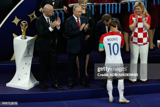 Croatia's midfielder Luka Modric is conforted by French President Emmanuel Macron next to Croatian President Kolinda Grabar-Kitarovic next Russian...