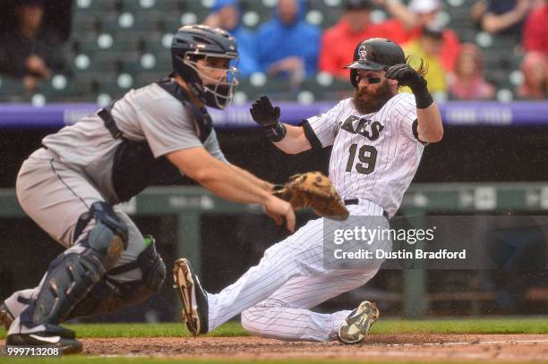 Charlie Blackmon of the Colorado Rockies slides into home plate to score a third inning run as David Freitas of the Seattle Mariners defends at Coors...