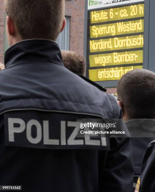 Police officers wait near the finding place of the aerial bomb, looking at a traffic infromation sign in wait of the defusion in Frankfurt am Main,...