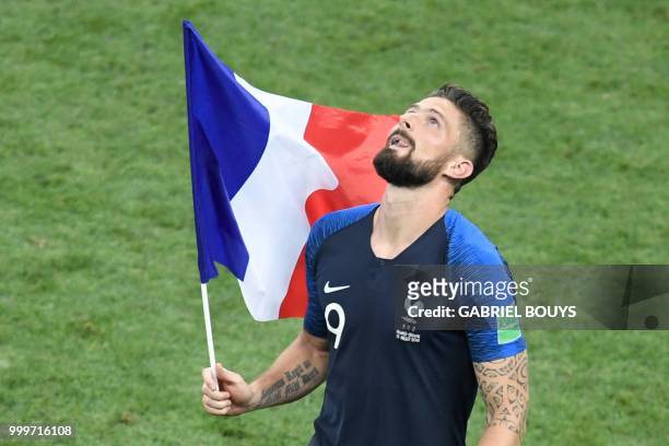 France's forward Olivier Giroud runs with the French national flag as he celebrates at the end of the Russia 2018 World Cup final football match...