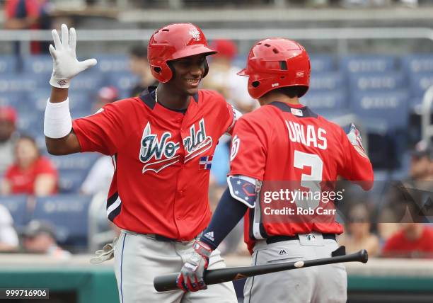 Seuly Matias of the Kansas City Royals and the World Team celebrates with teammate Leody Taveras of the Texas Rangers and the World Team after after...