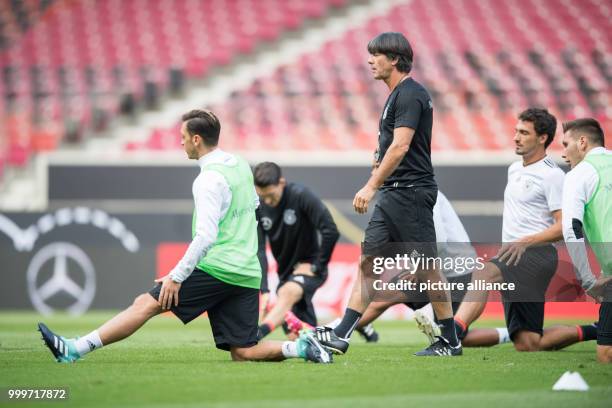 Germany's coach Joachim Loew watches his players doing warm-ups during a training session in the Mercedes-Benz Arena in Stuttgart, Germany, 03...