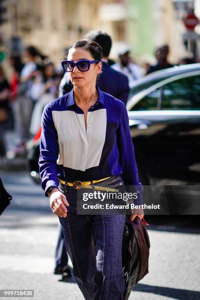 Guest wears blue sunglasses, a blue and white shirt, a golden belt, outside Dior, during Paris Fashion Week - Menswear Spring-Summer 2019, on June...