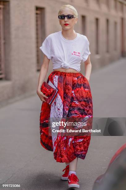 Guest wears sunglasses, a white knotted t-shirt, a red puffer skirt, red sneakers shoes, outside Wooyoungmi, during Paris Fashion Week - Menswear...