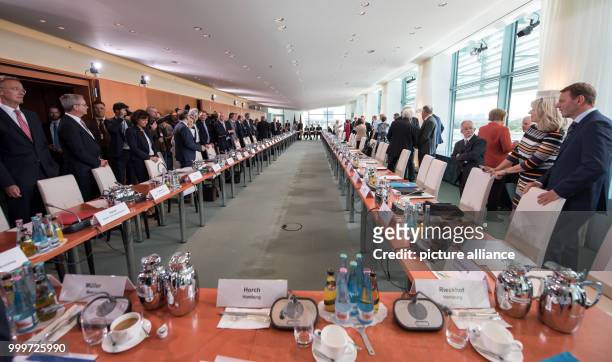 Representatives of the federal government, the state governments and the municipalities sit together at a meeting of the German chancellor with...