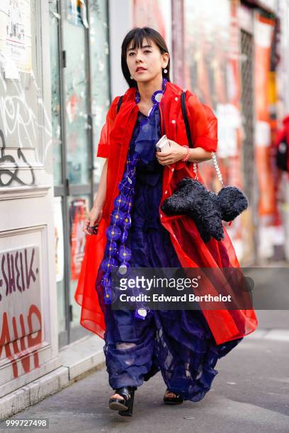 Guest wears a blue dress and a red coat, outside Yohji Yamamoto, during Paris Fashion Week - Menswear Spring-Summer 2019, on June 21, 2018 in Paris,...