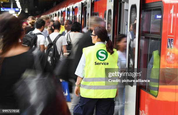 Customers pass Janine Feger, member of the DB Security Service, who is working in her function as entrance guide in a public transport train in...