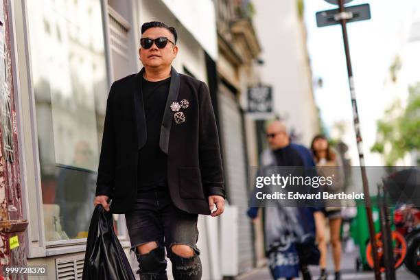 Guest wears sunglasses, a black blazer jacket, ripped jeans, outside Yohji Yamamoto, during Paris Fashion Week - Menswear Spring-Summer 2019, on June...