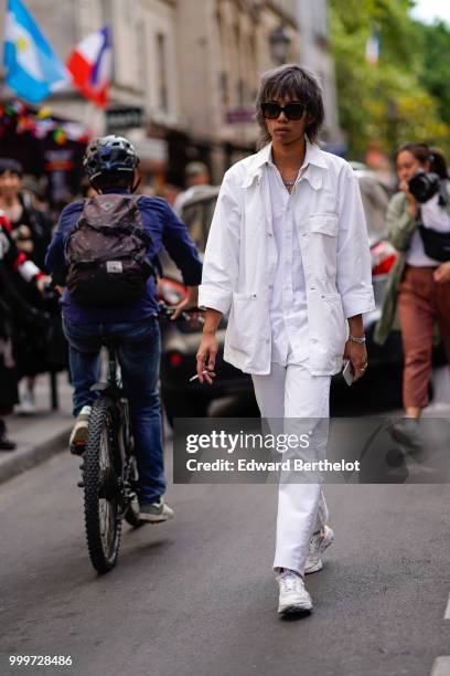 Guest wears a white jacket, white shirt, white pants, white sneakers shoes, outside Yohji Yamamoto, during Paris Fashion Week - Menswear...