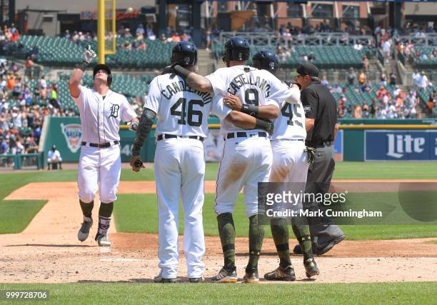 Jeimer Candelario, Nicholas Castellanos and Dixon Machado of the Detroit Tigers wait at home plate to greet teammate James McCann after he hit a...