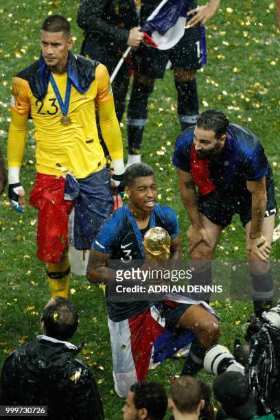 France's defender Presnel Kimpembe poses with the trophy at the end of the Russia 2018 World Cup final football match between France and Croatia at...