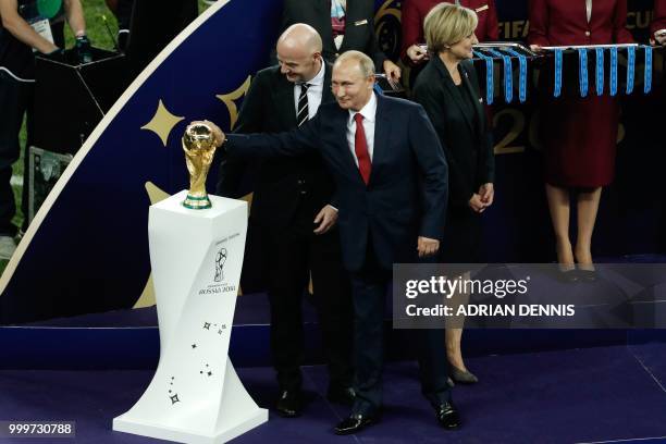 President Gianni Infantino watches as Russian President Vladimir Putin touches the World Cup trophy during the Russia 2018 World Cup final football...