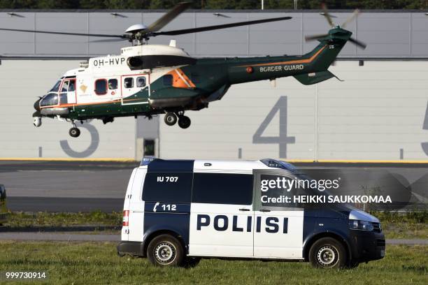 Police car and a border guard helicopter wait for the arrival of the US President at Helsinki-Vantaa Airport in Helsinki, on July 15, 2018 on the eve...