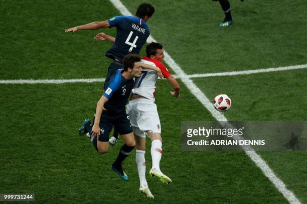 Croatia's forward Mario Mandzukic fights for the ball with France's defender Raphael Varane and France's defender Benjamin Pavard during the Russia...