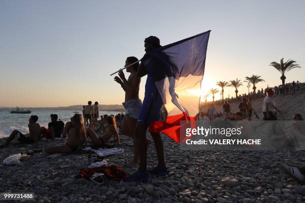 People wave a French flag on the beach after France won the Russia 2018 World Cup final football match against Croatia, on July 15, 2018 in Nice, on...