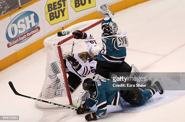 Goaltender Evgeni Nabokov of the San Jose Sharks attempts to make a save as Patrick Sharp of the Chicago Blackhawks crashes into the net along with...