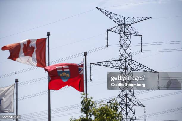 Canadian and Ontario flags fly in front of a Hydro One Ltd. Transmission tower in Toronto, Ontario, Canada, on Thursday, July 12, 2018. Hydro One is...