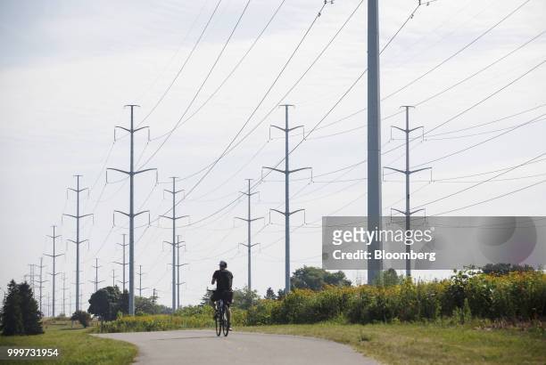 Cyclist rides past Hydro One Ltd. Transmission towers in Toronto, Ontario, Canada, on Thursday, July 12, 2018. Hydro One is facing a long-term share...