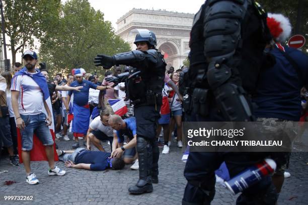 French gendarmes stand next to a man who was injured in a clash on the Champs-Elysees avenue in Paris on July 15 after France won the Russia 2018...