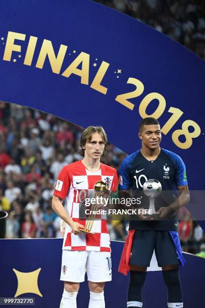 France's forward Kylian Mbappe poses with the FIFA Young Player award beside Croatia's midfielder Luka Modric holding the adidas Golden Ball prize...
