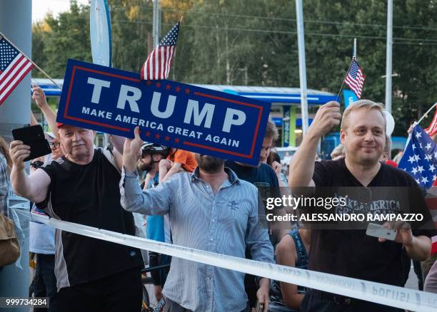 Supporters of US President Donald Trump hold an US flag as the Presidential motorcade passes by in Helsinki, Finland on July 15 on the eve of the...