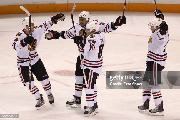 Dustin Byfuglien of the Chicago Blackhawks reacts with teammates Niklas Hjalmarsson, Patrick Kane and Jonathan Toews after Byfuglien scores a second...