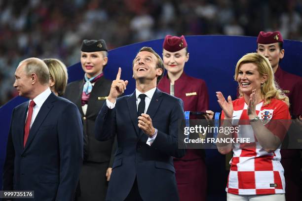 French President Emmanuel Macron gestures between Croatian President Kolinda Grabar-Kitarovic and Russian President Vladimir Putin during the trophy...