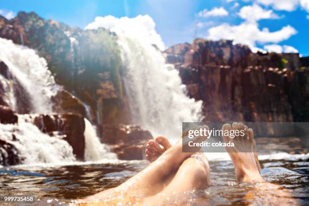 couple relaxing with feet up at cascata dos couros - chapada dos veadeiros - cascata stock pictures, royalty-free photos & images