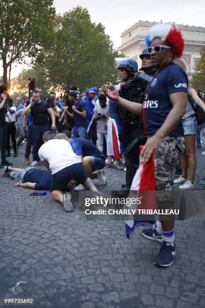 French gendarmes stand next to a man who was injured in a clash on the Champs-Elysees avenue in Paris on July 15 after France won the Russia 2018...