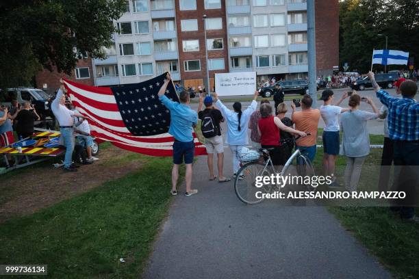 Supporters of US President Donald Trump hold an US flag as the Presidential motorcade passes by in Helsinki, Finland on July 15 on the eve of the...