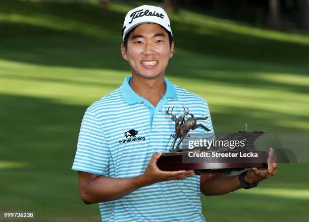 Michael Kim celebrates with the trophy after winning the John Deere Classic during the final round at TPC Deere Run on July 15, 2018 in Silvis,...