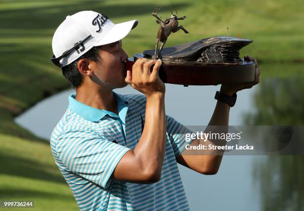 Michael Kim celebrates with the trophy after winning the John Deere Classic during the final round at TPC Deere Run on July 15, 2018 in Silvis,...