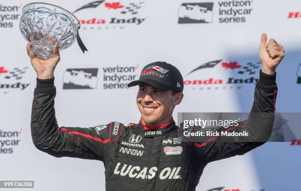 Canadian Robert Wickens with his trophy for taking 3rd at the Honda Indy Toronto. Scott Dixon, of New Zealand, takes the checkered flag at Honda Indy...