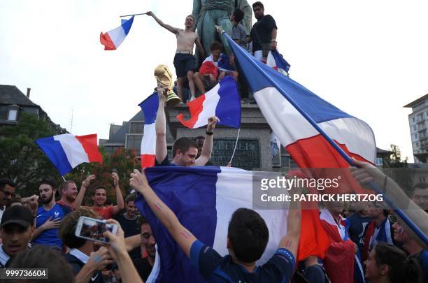 Peopler wave French national flags as they celebrate after France won the Russia 2018 World Cup final football match between France and Croatia, on...