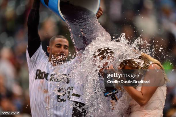 Trevor Story of the Colorado Rockies is doused with ice water by Ian Desmond as he gives a TV interview to Taylor McGregor, after hitting a...