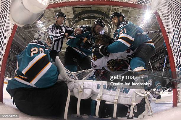 Adam Burish of the Chicago Blackhawks is knocked down by Douglas Murray and Scott Nichol of the San Jose Sharks as goaltender Evgeni Nabokov is in...