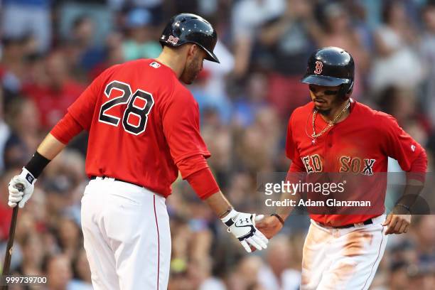 Mookie Betts high fives J.D. Martinez of the Boston Red Sox after scoring in the second inning of a game against the Toronto Blue Jays at Fenway Park...