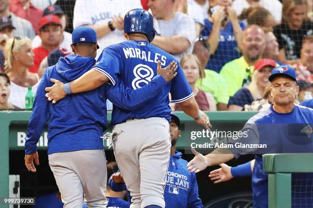 Kendrys Morales of the Toronto Blue Jays returns to the dugout after scoring in the third inning of a game against the Boston Red Sox at Fenway Park...