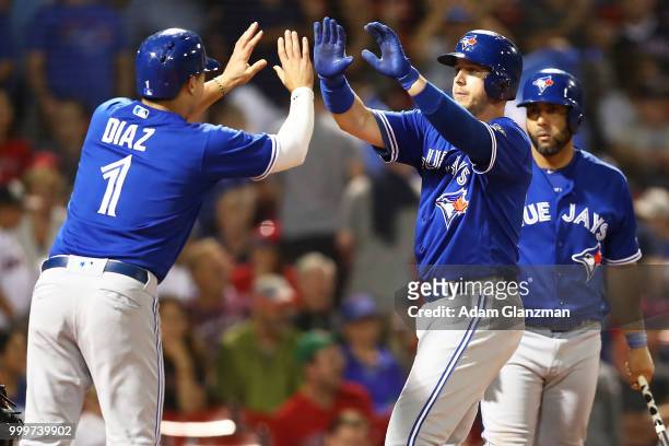 Justin Smoak high fives Aledmys Diaz of the Toronto Blue Jays after hitting a two-run home run in the ninth inning of a game against the Boston Red...