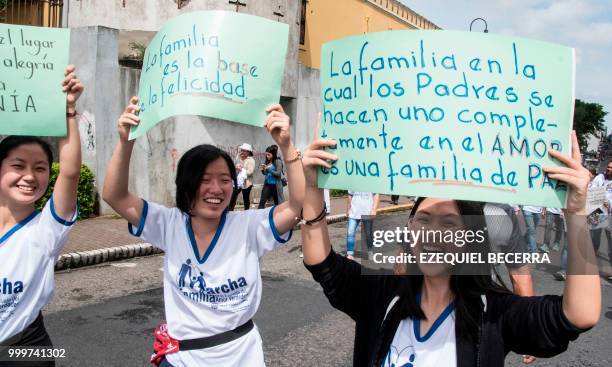 Women hold signs in favor of the traditional family during a march in San Jose, on July 15, 2018.