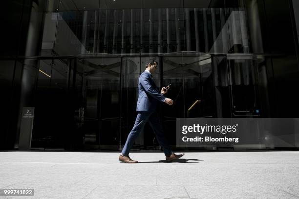 Pedestrian holds a smartphone as he walks in the financial district of Toronto, Ontario, Canada, on Wednesday, July 11, 2018. Canadian stocks were...