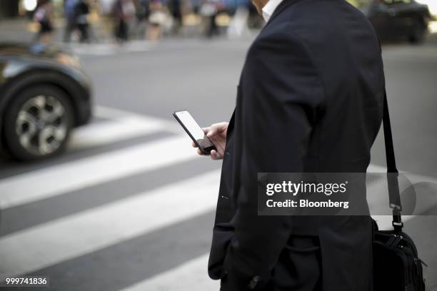 Pedestrian looks at a smartphone while standing at a corner in the financial district of Toronto, Ontario, Canada, on Wednesday, July 11, 2018....