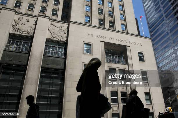 The silhouettes of pedestrians are seen walking past the Bank of Nova Scotia building in the financial district of Toronto, Ontario, Canada, on...