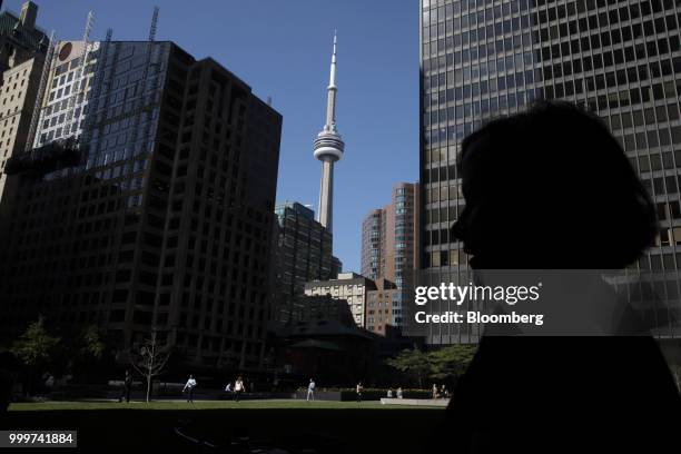 The silhouette of a pedestrian is seen in front of the CN Tower in the financial district of Toronto, Ontario, Canada, on Wednesday, July 11, 2018....