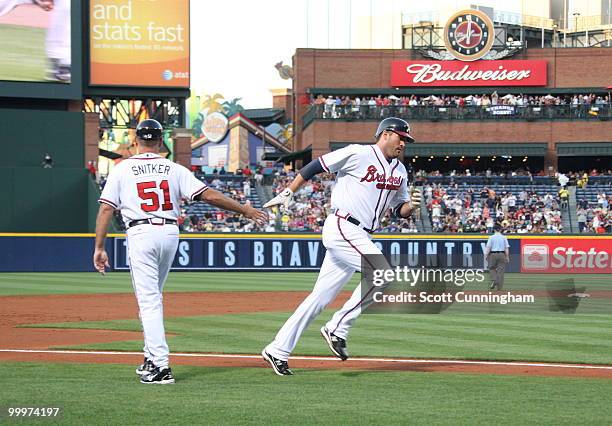 Troy Glaus of the Atlanta Braves is congratulated by third base coach Brian Snitker after hitting a third-inning home run against the New York Mets...