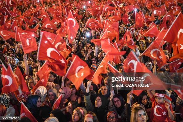 People wave Turkish national flags as they stand near the "July 15 Martyrs Bridge" in Istanbul on July 15, 2018. - Turkey on commemorated the second...