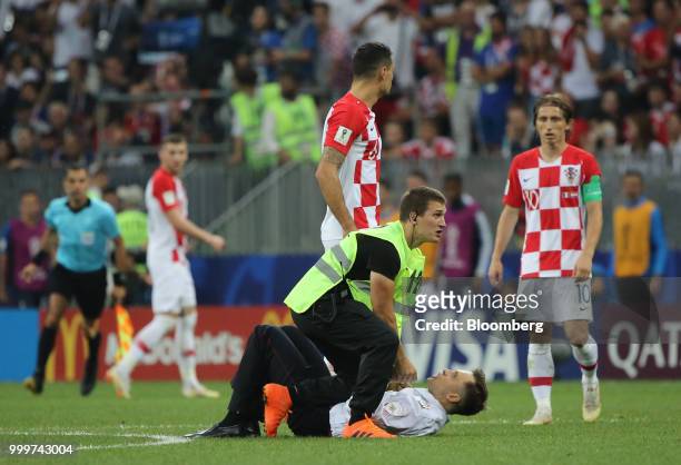 Players from the Croatia team stand as security guards remove a protester from the pitch during the FIFA World Cup final match in Moscow, Russia, on...